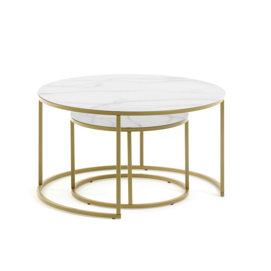 the Leonor coffee table features two round tables with a nested composition, allowing for one table to be stored underneath, to save space. It features a gold metal finish, and the tops are constructed with glass in a marble glaze underneath. 