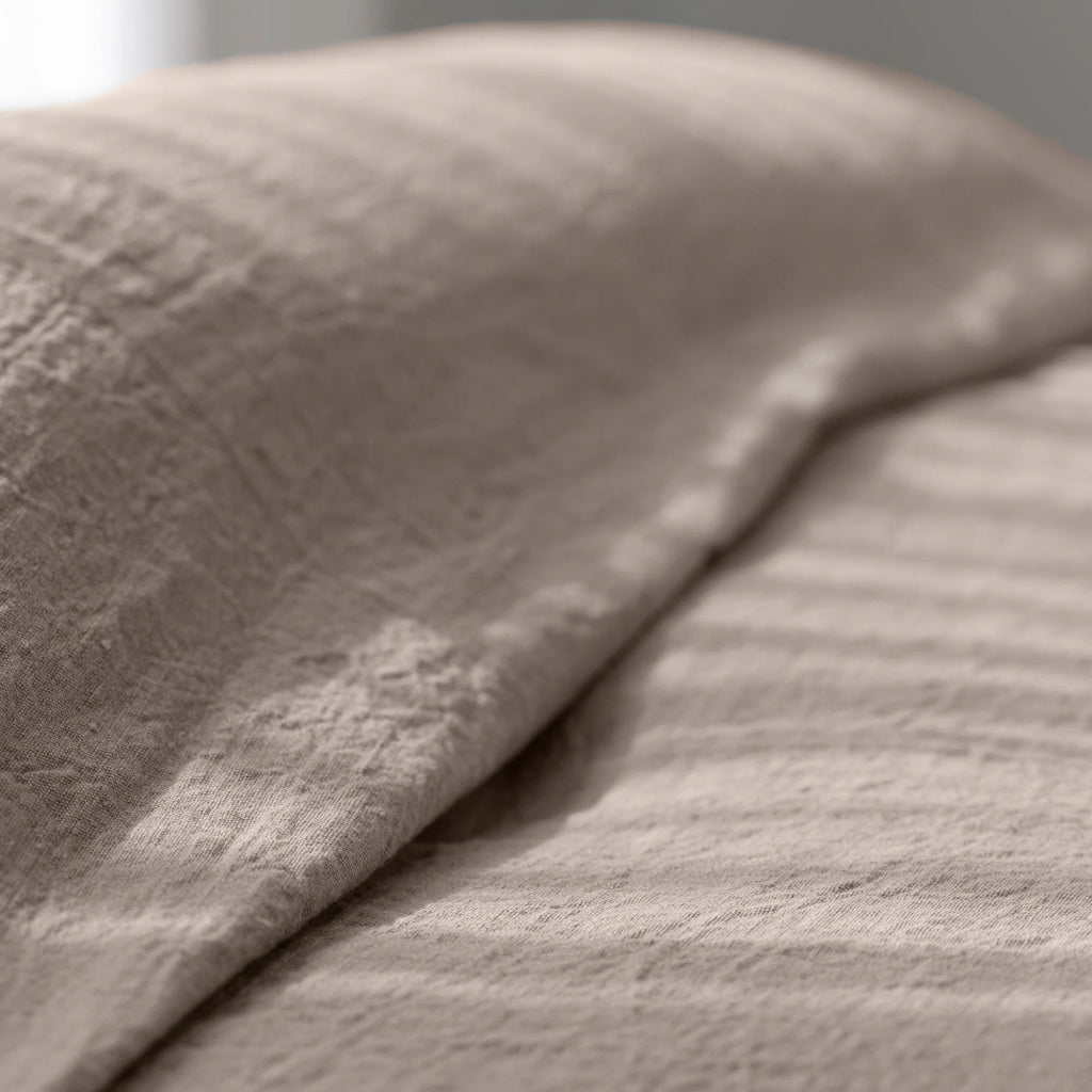 Luca bed cover in natural beige linen with relaxed, casual draping.