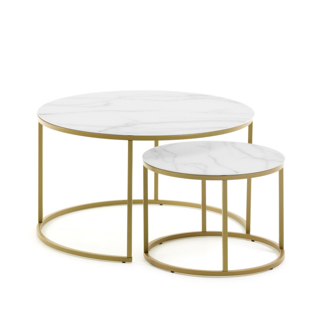 the Leonor coffee table features two round tables with a nested composition, allowing for one table to be stored underneath, to save space. It features a gold metal finish, and the tops are constructed with glass in a marble glaze underneath. 